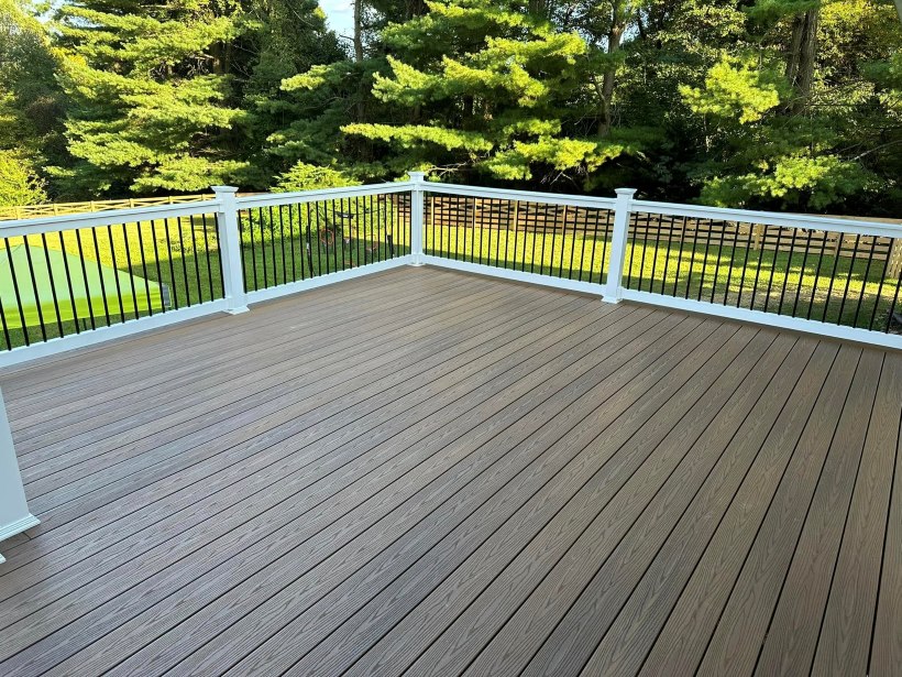 Newly installed brown wooden deck with white railing